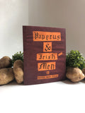 Maroon paper zine with text and decorative elements on a white surface with pototes and plants.