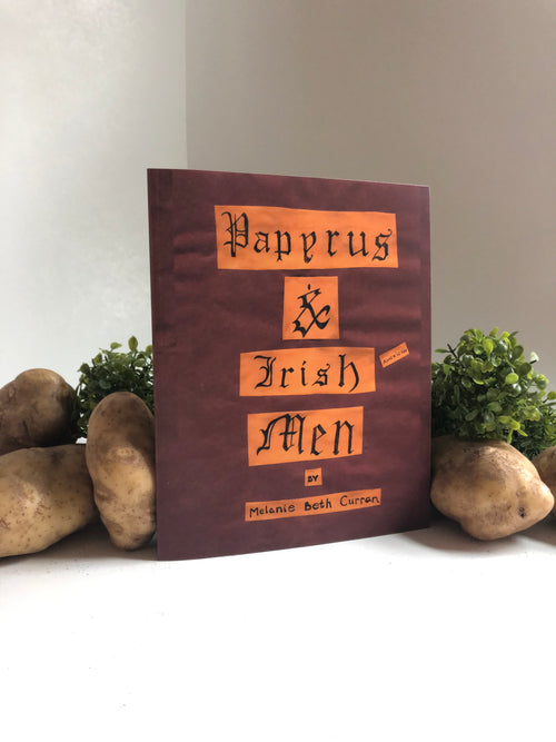 Maroon paper zine with text and decorative elements on a white surface with pototes and plants.